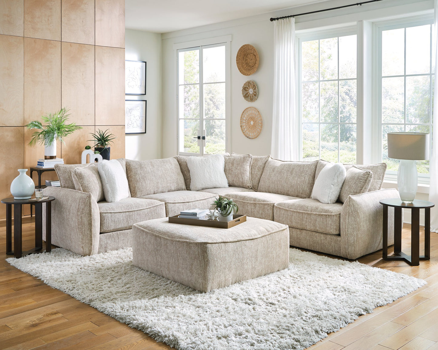 Beige sectional sofa in a living room with a white rug and decorative items.