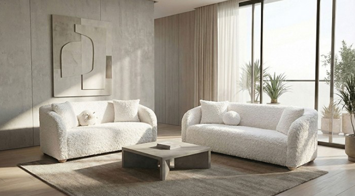 Modern living room with white sofas, a coffee table, and large windows.
