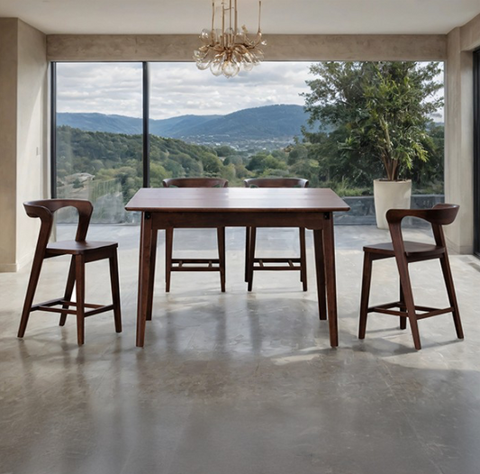 Wooden dining table with chairs in a modern room with large windows overlooking a scenic view.