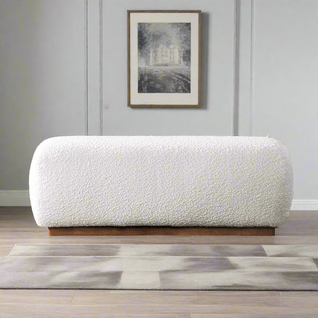 White textured ottoman in a living room with a fireplace and shelves.