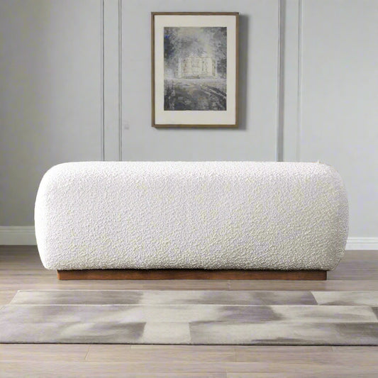 White textured ottoman in a living room with a fireplace and shelves.