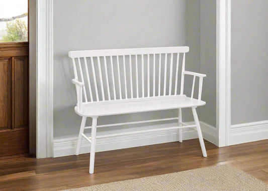 White bench in a home entryway with wooden floor and staircase.