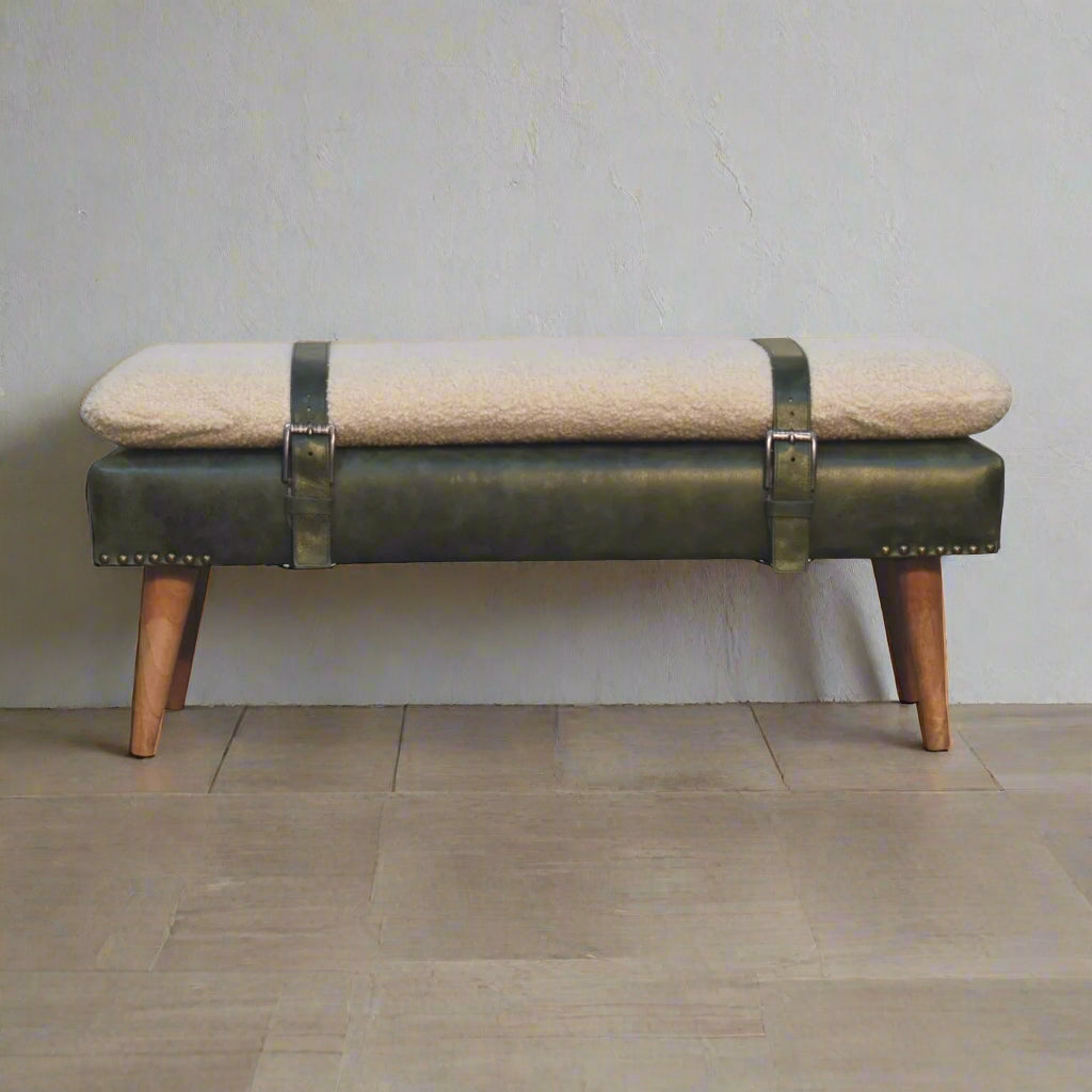 Bench with green leather straps and beige cushion on a wooden floor.