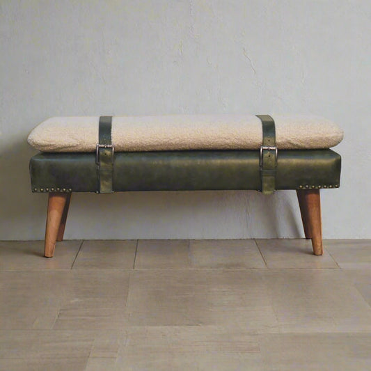 Bench with green leather straps and beige cushion on a wooden floor.