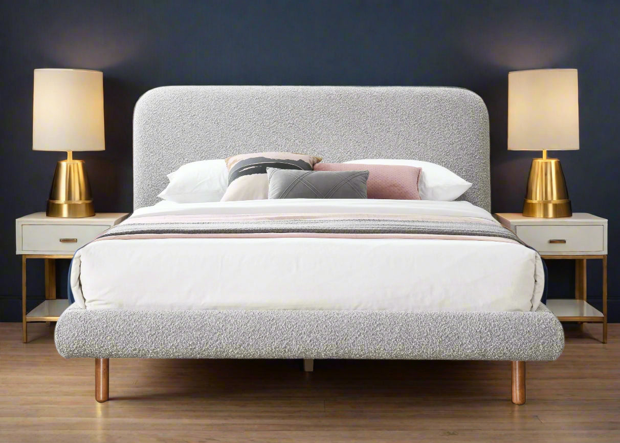 Gray upholstered bed with white bedding and colorful pillows on a white background