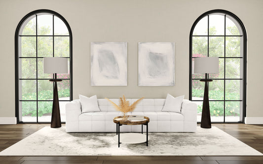 Modern living room with a white sofa, arched windows, and abstract art on the wall.