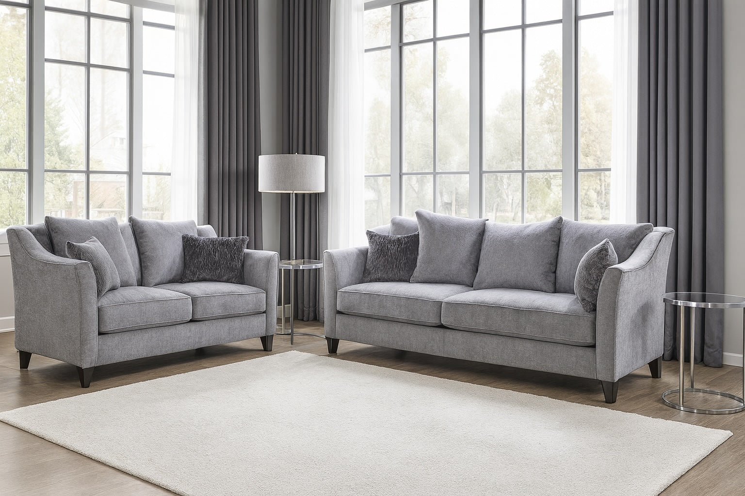 Gray sofa set in a living room with large windows and curtains.