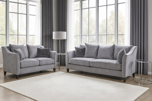 Gray sofa set in a living room with large windows and curtains.