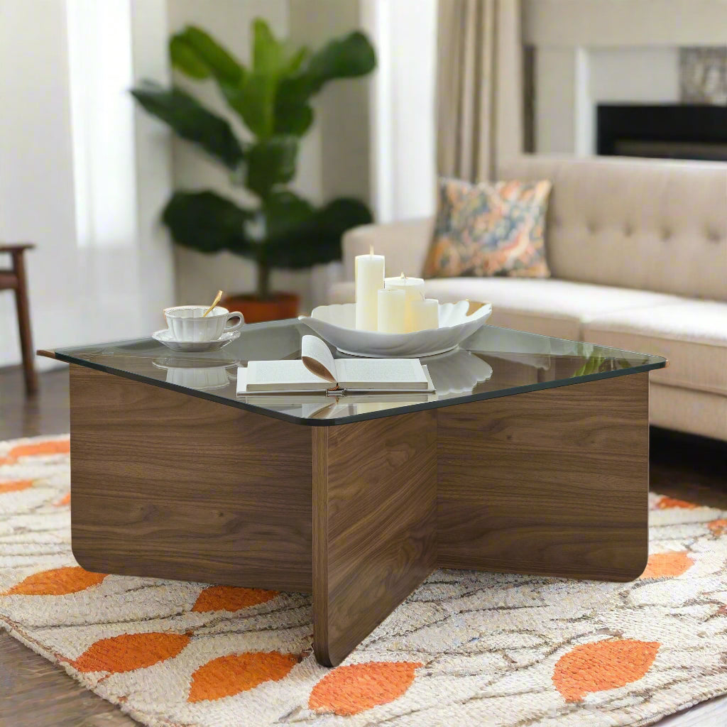Modern living room with a glass coffee table, candles, and books.