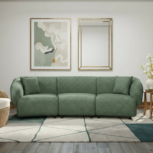 Green sofa in a room with large windows overlooking a beach.