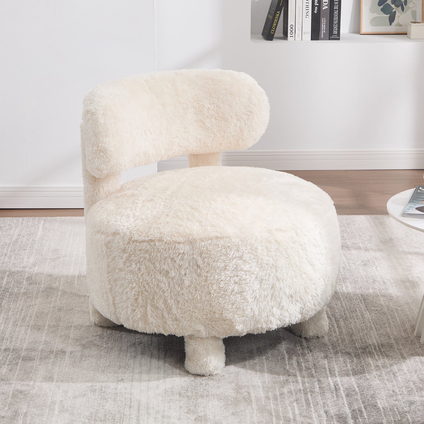White fluffy chair in a room with a rug and books on a shelf.