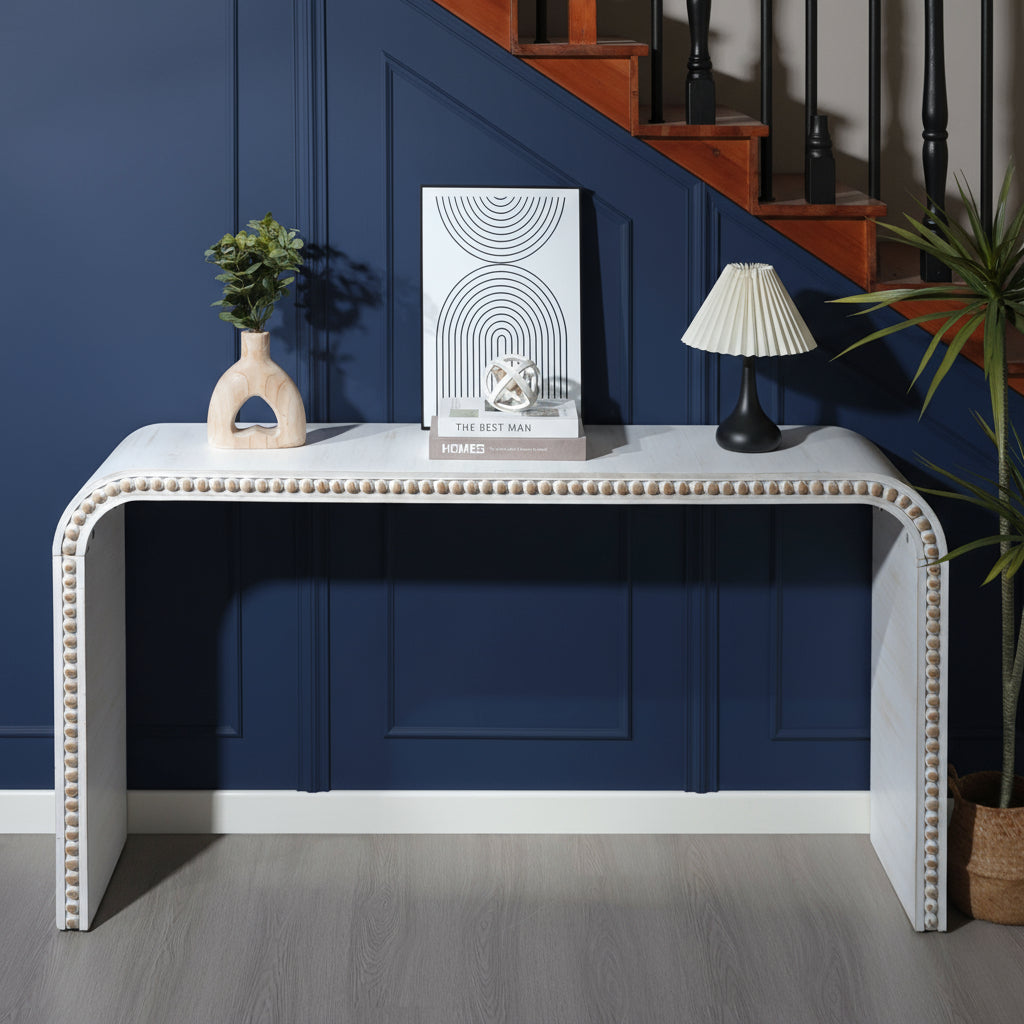 White console table with decorative items against a wall with wainscoting.
